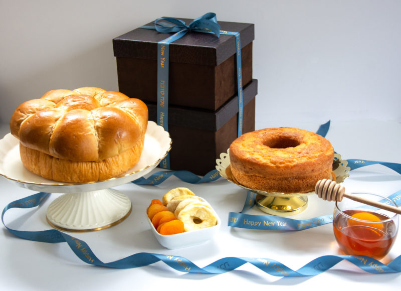 Rosh Hashana Gift box with honey cake, jar of honey, Challah, honey dropper, and dried apples and apricots