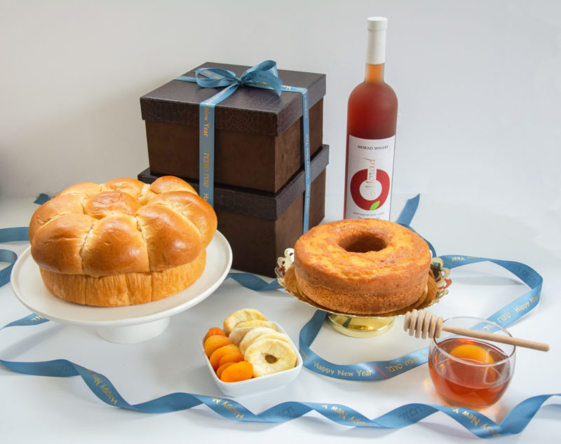 Rosh Hashana Gift box with honey cake, wine, jar of honey, Challah, honey dropper, and dried apples and apricots