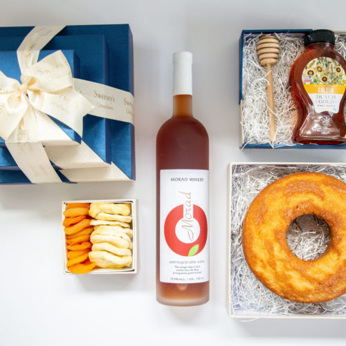 Rosh hashana gift box with honey cake, honey, honey dropper, dried apples and apricots and Israeli pomegranate wine