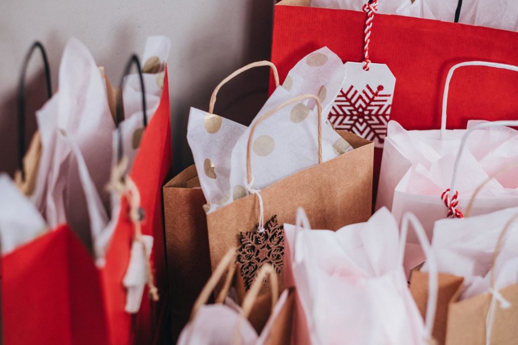 A selection of gift bags in brown, white, and red with complimentary tissue paper and tags.